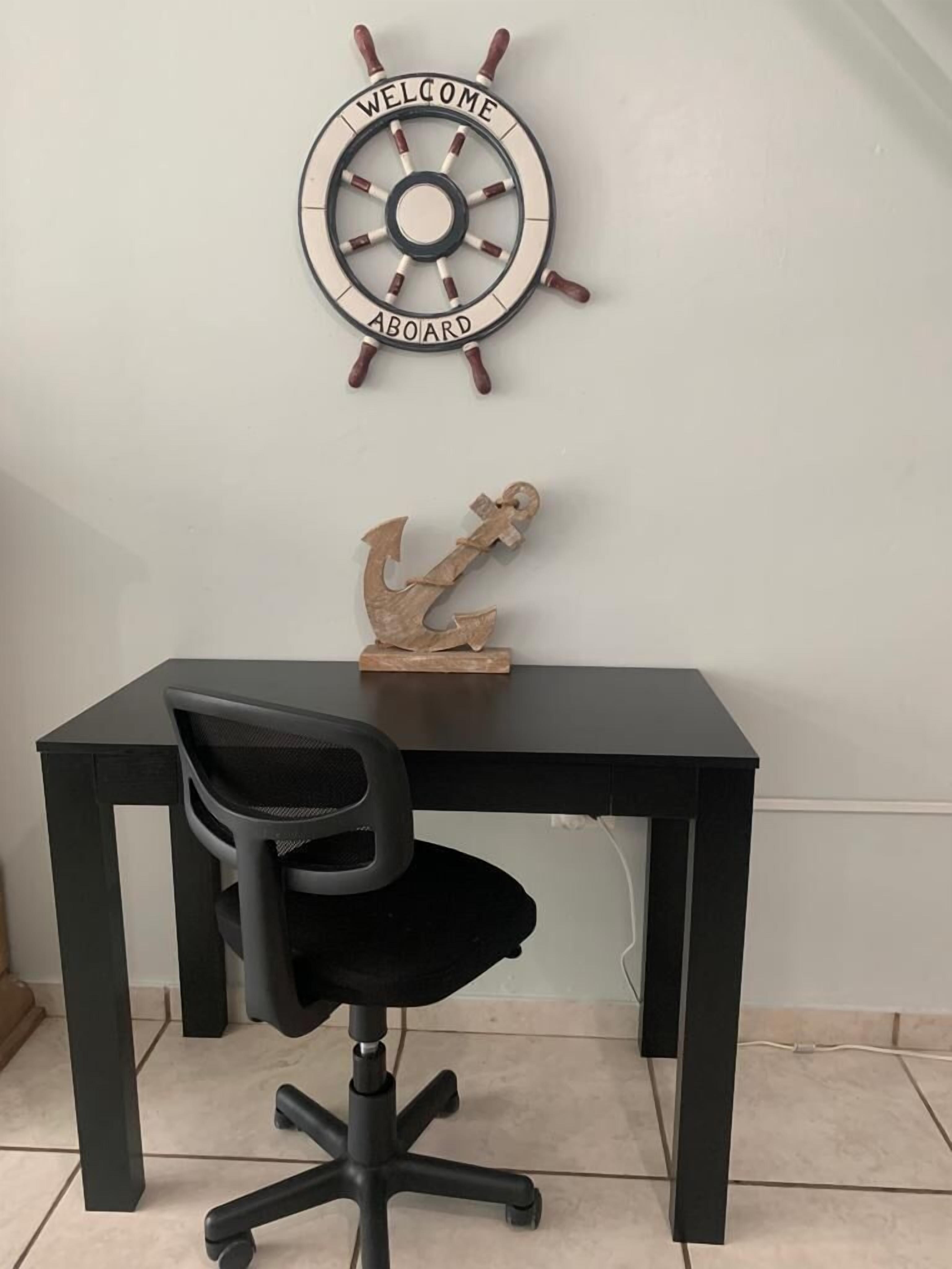 A desk with a black office chair, a ship's wheel with 'WELCOME ABOARD' text, and a small anchor decoration.