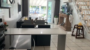 A modern kitchen with a central island, a dining area with a sofa, and a staircase leading to an upper level.