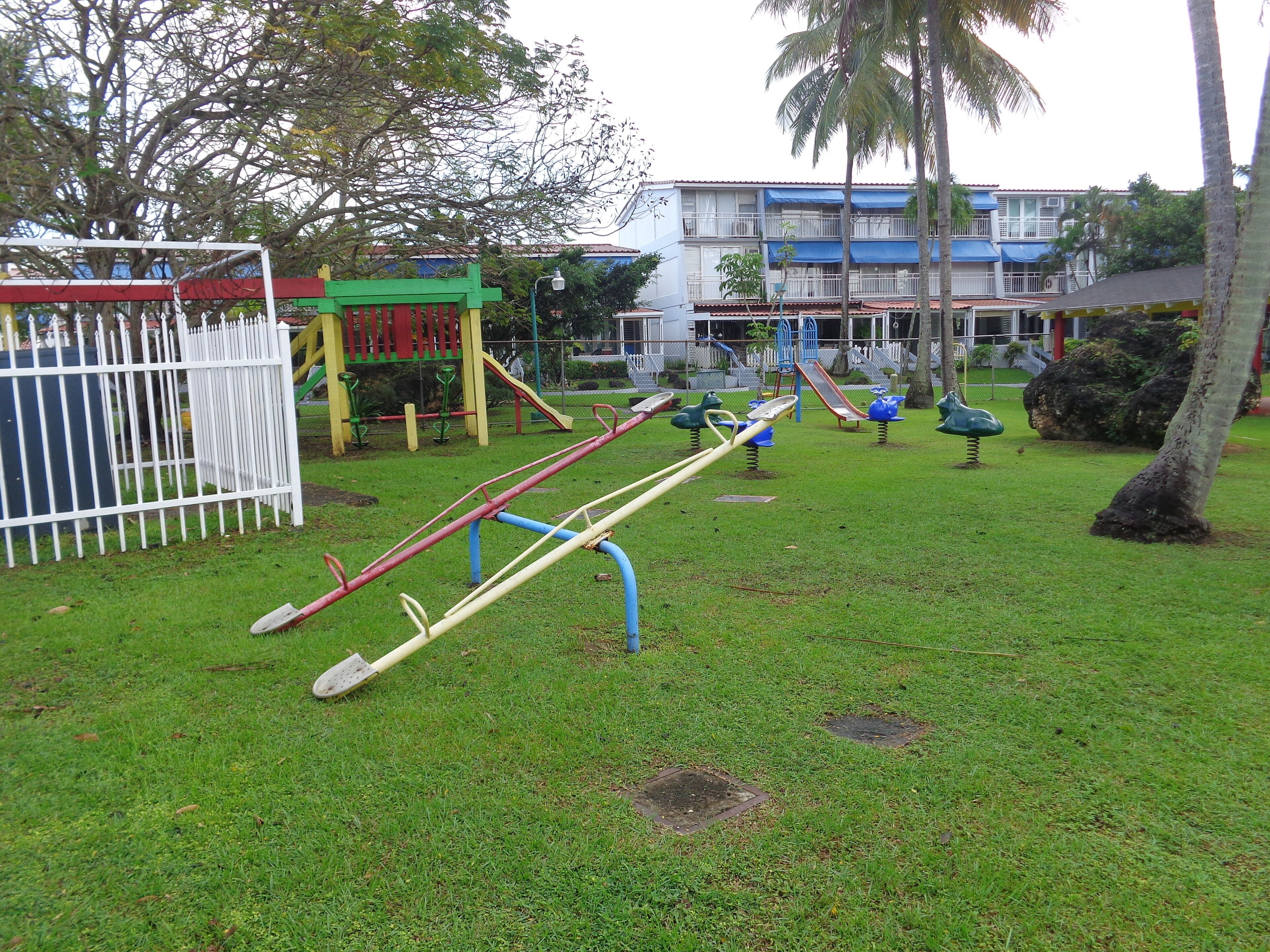 A playground with swings, slides, and a fenced area.
