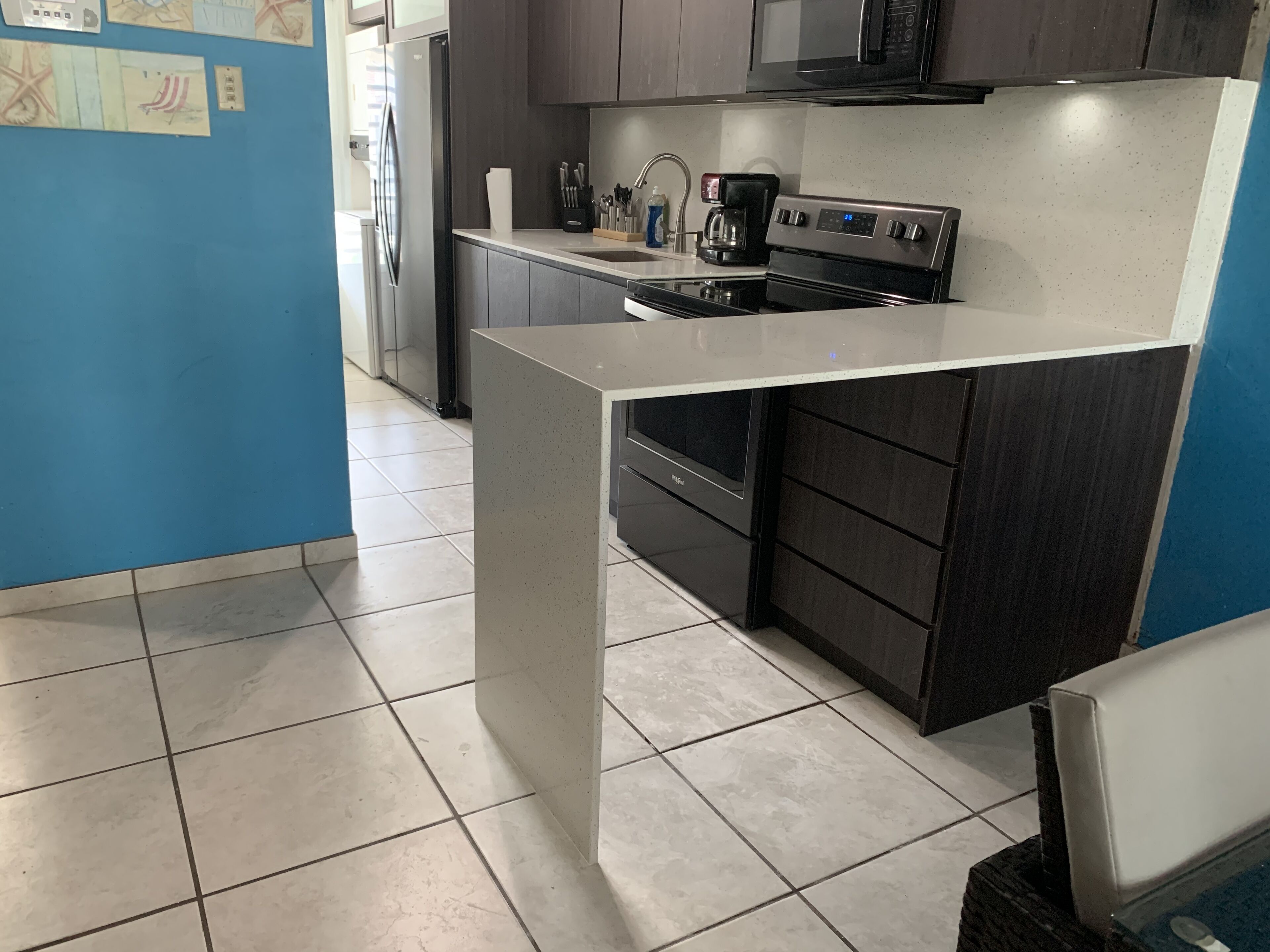 Una cocina moderna con una isla central, electrodomésticos de acero inoxidable y armarios oscuros.