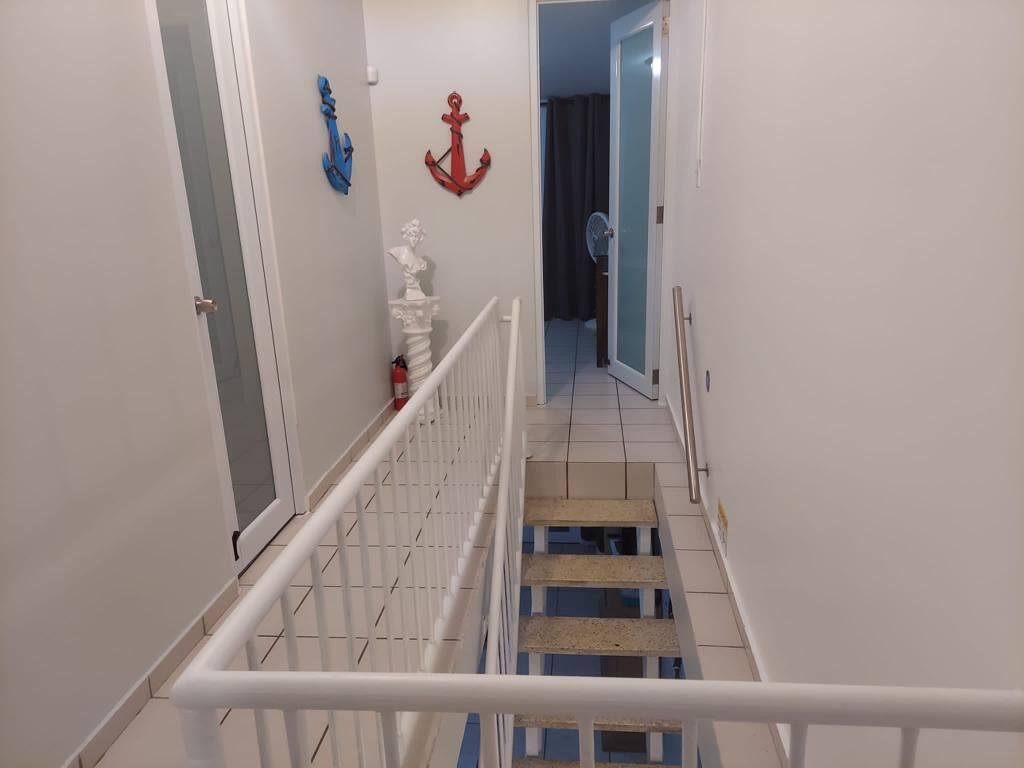 A narrow hallway with white walls, a white railing, and a blue and white striped floor.