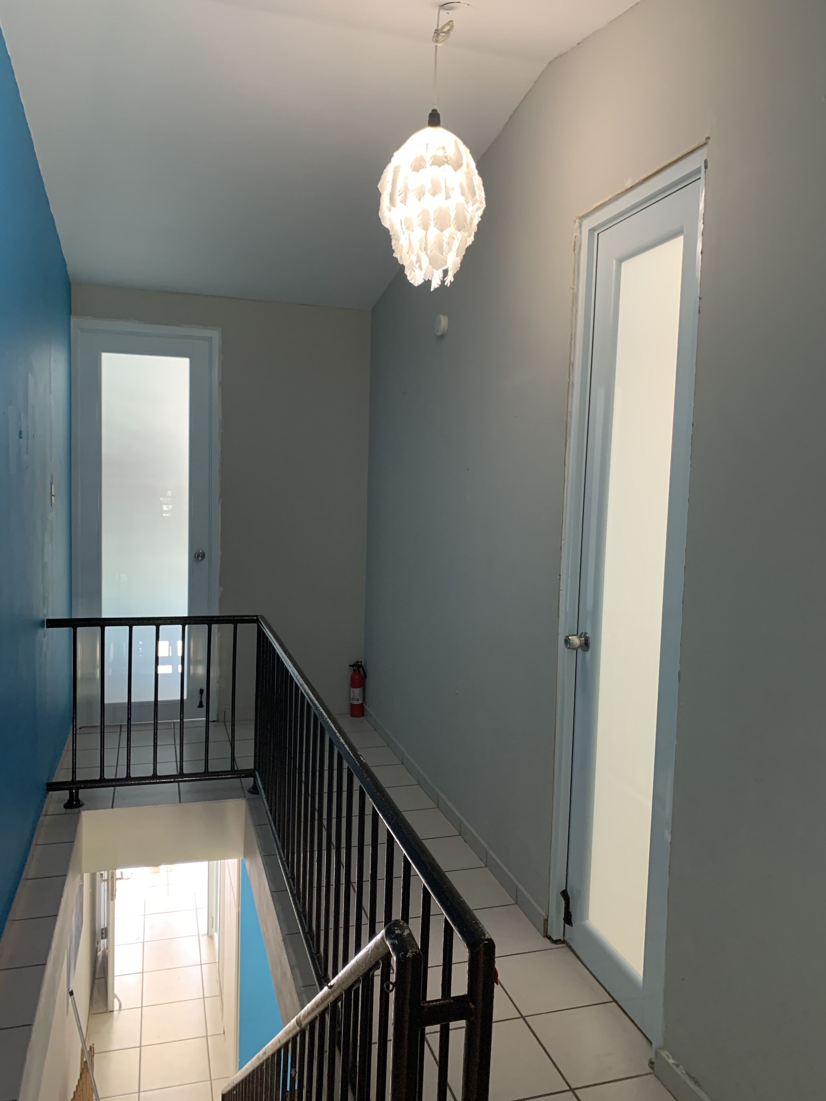 Un escalier avec une rampe noire, un plafond blanc et un sol blanc.