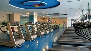 A gym with multiple treadmills arranged in rows, a blue ceiling with circular designs, and a clean, modern interior. - Qingdao Tiantai Meijia Apartment Hotel (Heilongjiang Road Tiantai City Branch) (Qingdao)