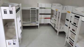 A room with bunk beds, a white wardrobe, and a white desk.