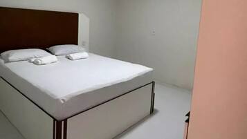 Un dormitorio con cama, cabecero, armario y luz de techo.