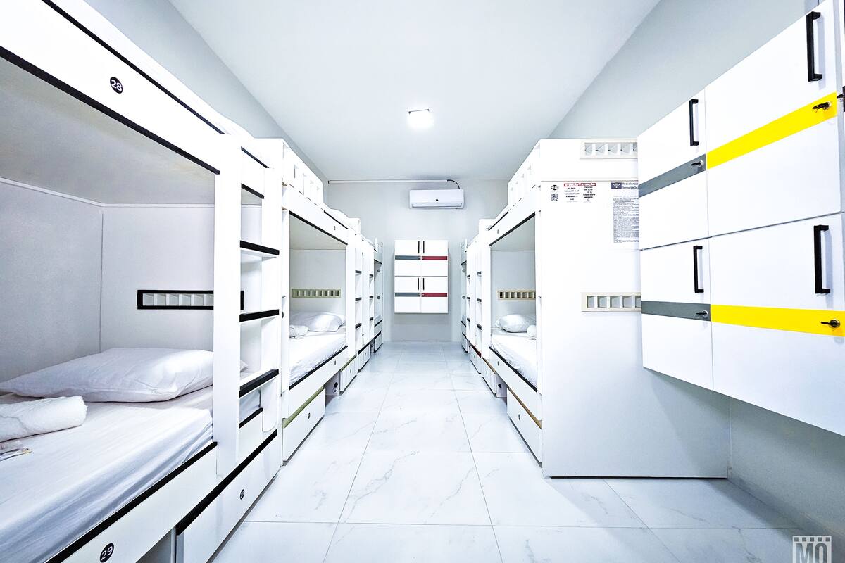 Una habitación de hotel con literas, piso de baldosas blancas y techo blanco.