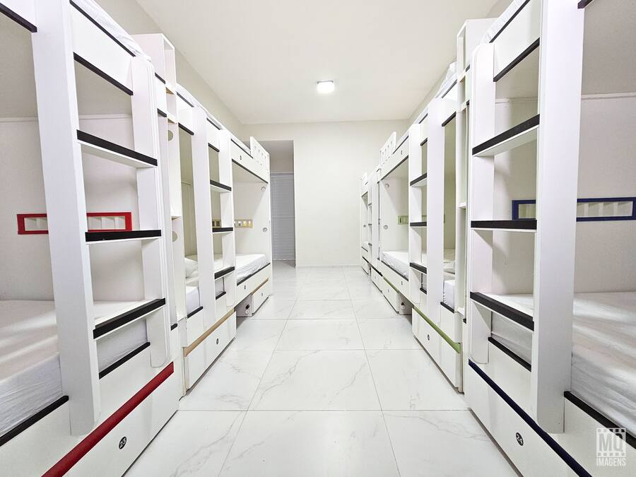 A corridor with bunk beds on either side, leading to a door at the end.