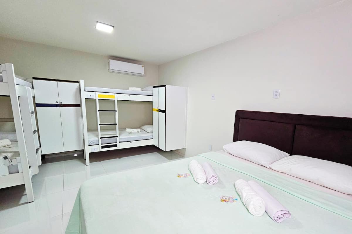 Un dormitorio con literas, un armario, una cama con almohadas y un ventilador de techo.