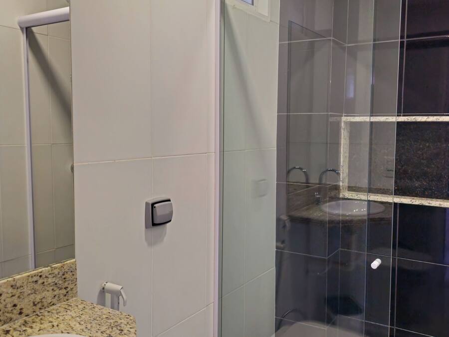 A bathroom with a glass-enclosed shower, a white toilet, and a granite countertop sink.