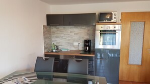 A compact kitchen with dark cabinets, a microwave, an oven, and a coffee maker.