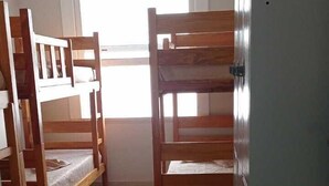 Una habitación con literas, un armario y un sillón de peluche.
