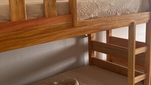 Una cama litera con estructura de madera y ropa de cama color crema.
