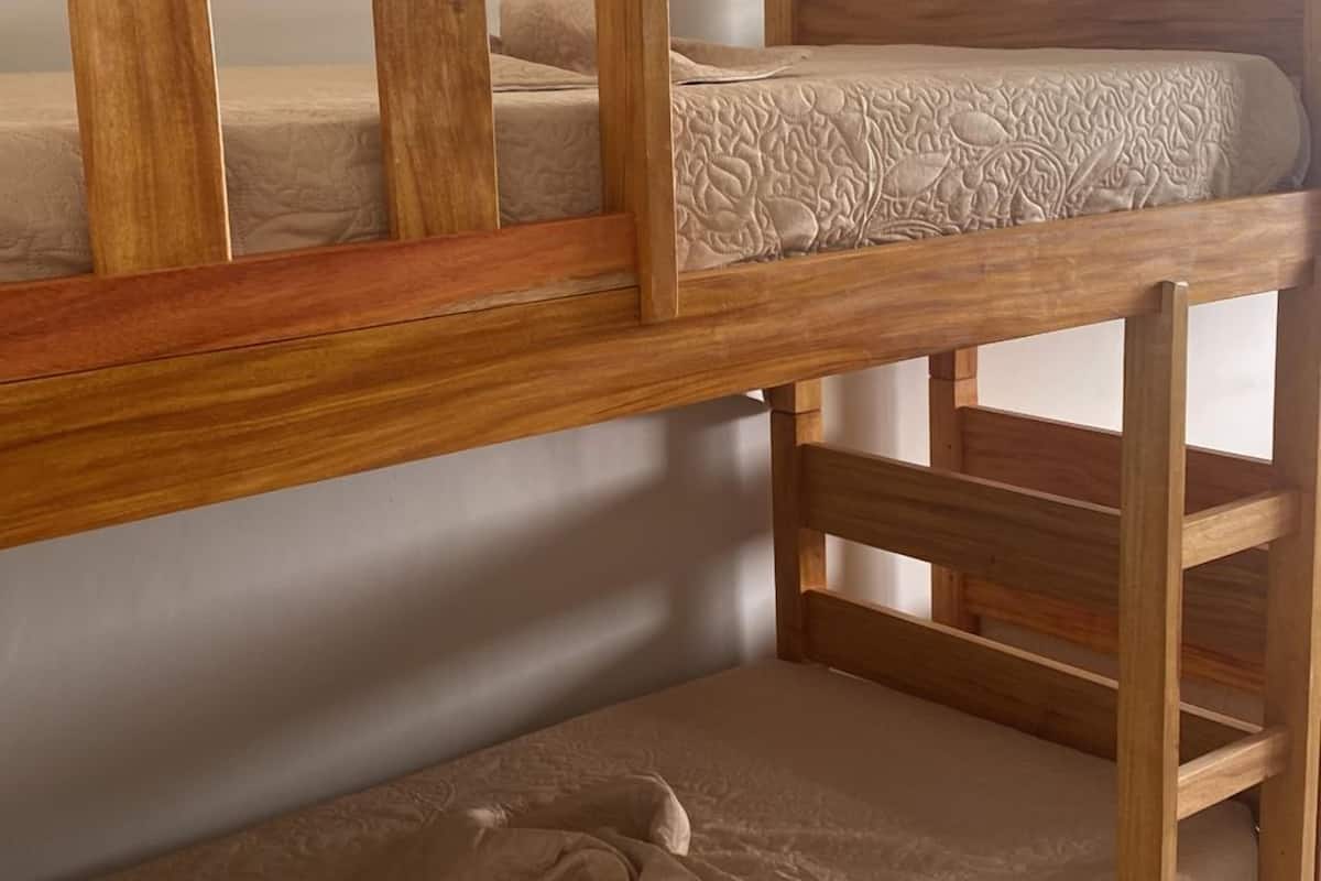 A bunk bed with a wooden frame and beige bedding.