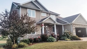 A two-story house with a stone facade, a front porch, and a garage.