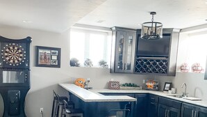 A modern kitchen with a bar area, wooden flooring, and a large window.