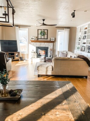 A spacious living room with a fireplace, a sofa, a coffee table, and a TV. - EAA | Private Home | 15 Minute Commute to Airventure (Neenah)