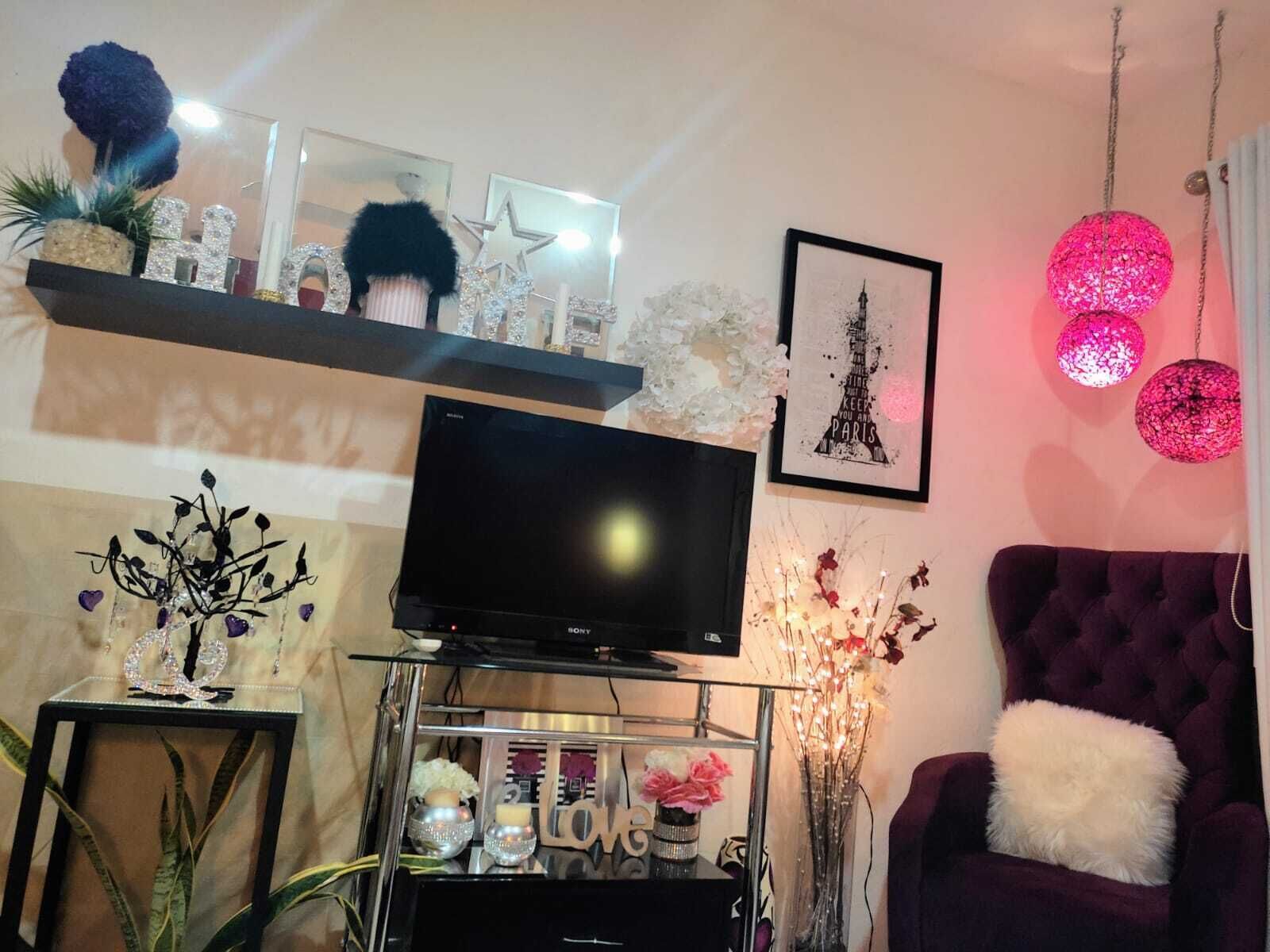 A living room with a flat-screen TV, decorative items, a framed picture, and a purple armchair.