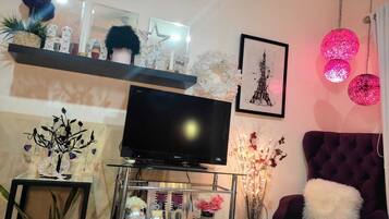 A living room with a flat-screen TV, decorative items, a framed picture, and a purple armchair.