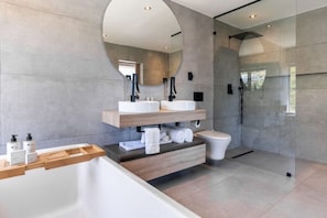 A modern bathroom with a large bathtub, two sinks, a toilet, and a glass-enclosed shower area. - The View CampsBay w/inifinity pool -5 mins from Beach (Cape Town)