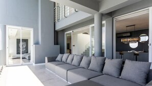 A modern living room with a grey sectional sofa, a staircase, and a dining area with a chandelier. - The View CampsBay w/inifinity pool -5 mins from Beach (Cape Town)