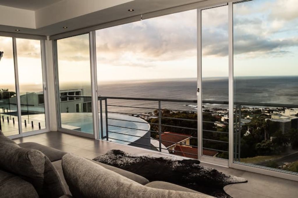 A modern living room with a large sliding glass door leading to a balcony with a pool view.
