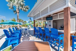 A poolside area with blue chairs, a wooden deck, and a bar area with a refrigerator. - Spacious 8 Bed Pool Home with Spa-3516LD (Davenport)