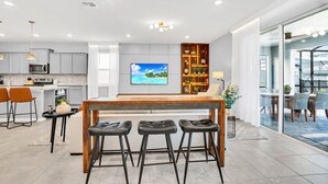 A modern kitchen with a central island, bar stools, and a dining area with a view.