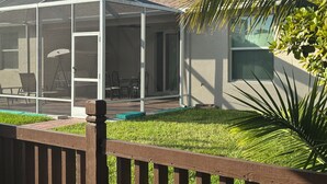 Una veranda riparata con piscina, mobili da esterno e una recinzione in legno.