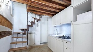 Una cucina con mobili bianchi, un fornello e un pavimento piastrellato.