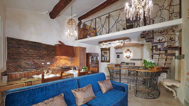 Un'ampia zona giorno con un divano blu, un tavolino in legno e un lampadario.