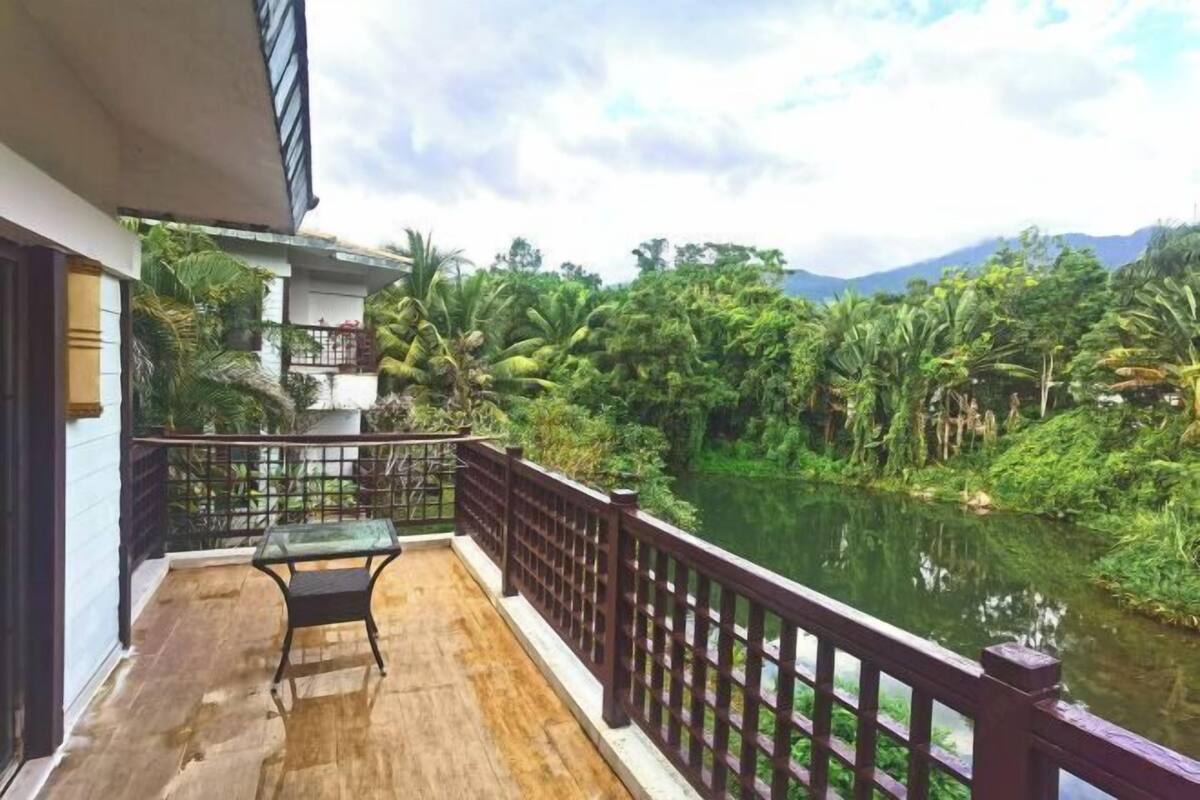 Ein Balkon mit Glastisch und Stühlen mit Blick auf einen Fluss und üppiges Grün.
