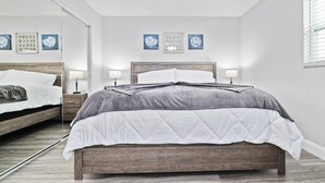Una camera da letto con un letto in legno, biancheria bianca, uno specchio e decorazioni alle pareti.