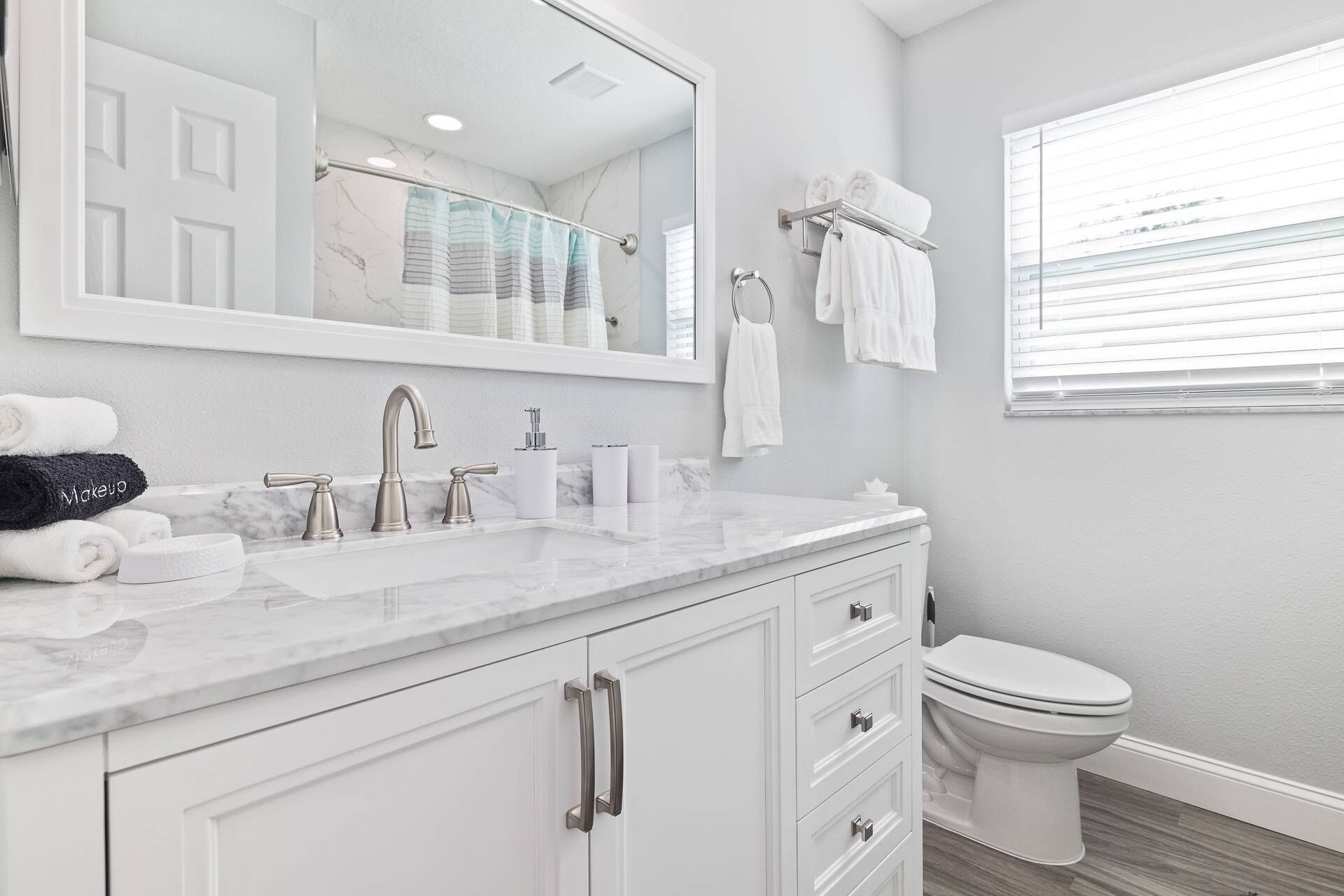 Une salle de bain moderne avec un lavabo en marbre, des toilettes et un grand miroir.