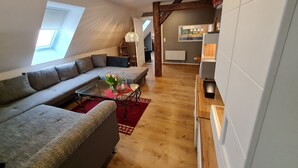 A modern living room with a sectional sofa, a glass coffee table, and a red rug. - Harzritter Domizil Großzügige Familienwohnung (Blankenburg OT Cattenstedt)