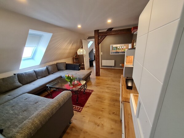A modern living room with a sectional sofa, a glass coffee table, and a red rug.