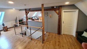 A loft-style room with a wooden floor, a mezzanine level, and a staircase. - Harzritter Domizil Großzügige Familienwohnung (Blankenburg OT Cattenstedt)