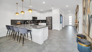 A modern kitchen with a central island, bar stools, stainless steel appliances, and pendant lighting. - Fun and Fabulous 9Bed Pool Home Game Room-2900PL (Kissimmee)