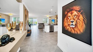 A spacious living area with a modern kitchen, a dining area, and a large window providing a view of the outdoors. - Fun and Fabulous 9Bed Pool Home Game Room-2900PL (Kissimmee)