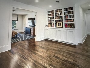 Cozy retreat with a bookshelf and doorway to a separate kitchen area.