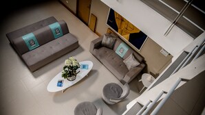 Una sala de estar moderna con un sofá, dos sillones, una mesa de centro y una mesita auxiliar.