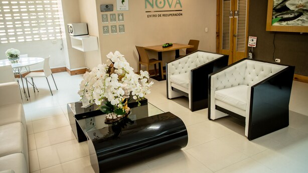 Un área de espera moderna con mostrador de recepción, asientos y una pared con el nombre 'Bela Nova'.