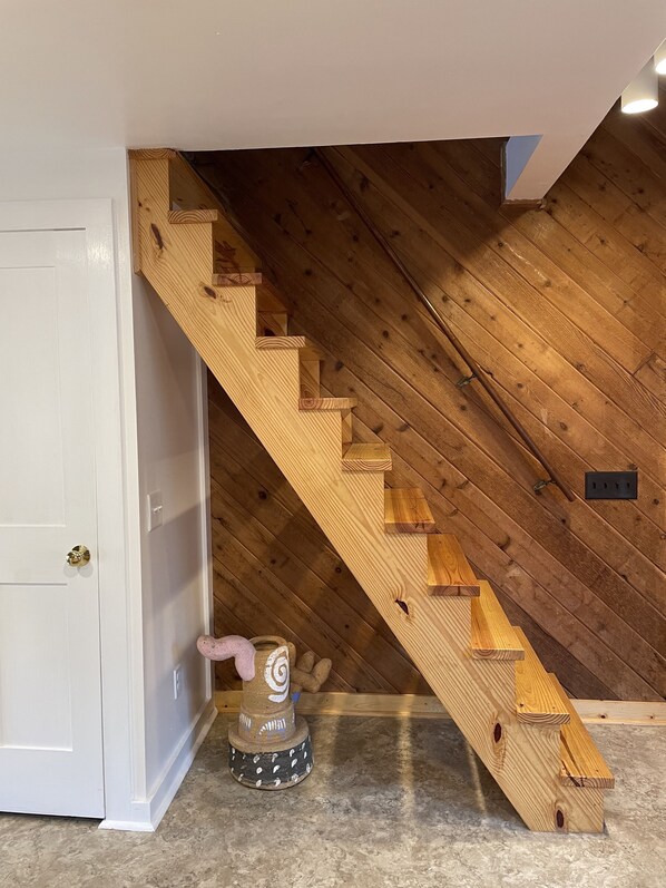 A wooden staircase with a white door on the left. - Mid-century A-frame style cabin with lake views near the heart of Amish Country (Stone Creek)
