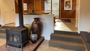 Un salon chaleureux avec une cheminée, un grand vase et un escalier menant à un balcon.