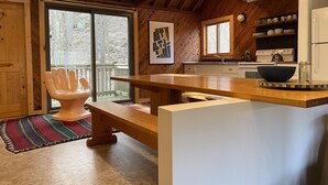 Une cuisine moderne avec des poutres en bois, une grande fenêtre et une chaise au style rustique.