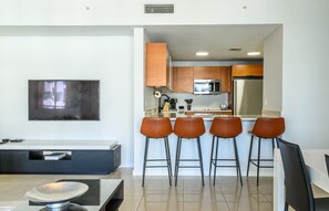Una cocina moderna con televisor de pantalla plana, armarios de madera y una zona de bar con taburetes.