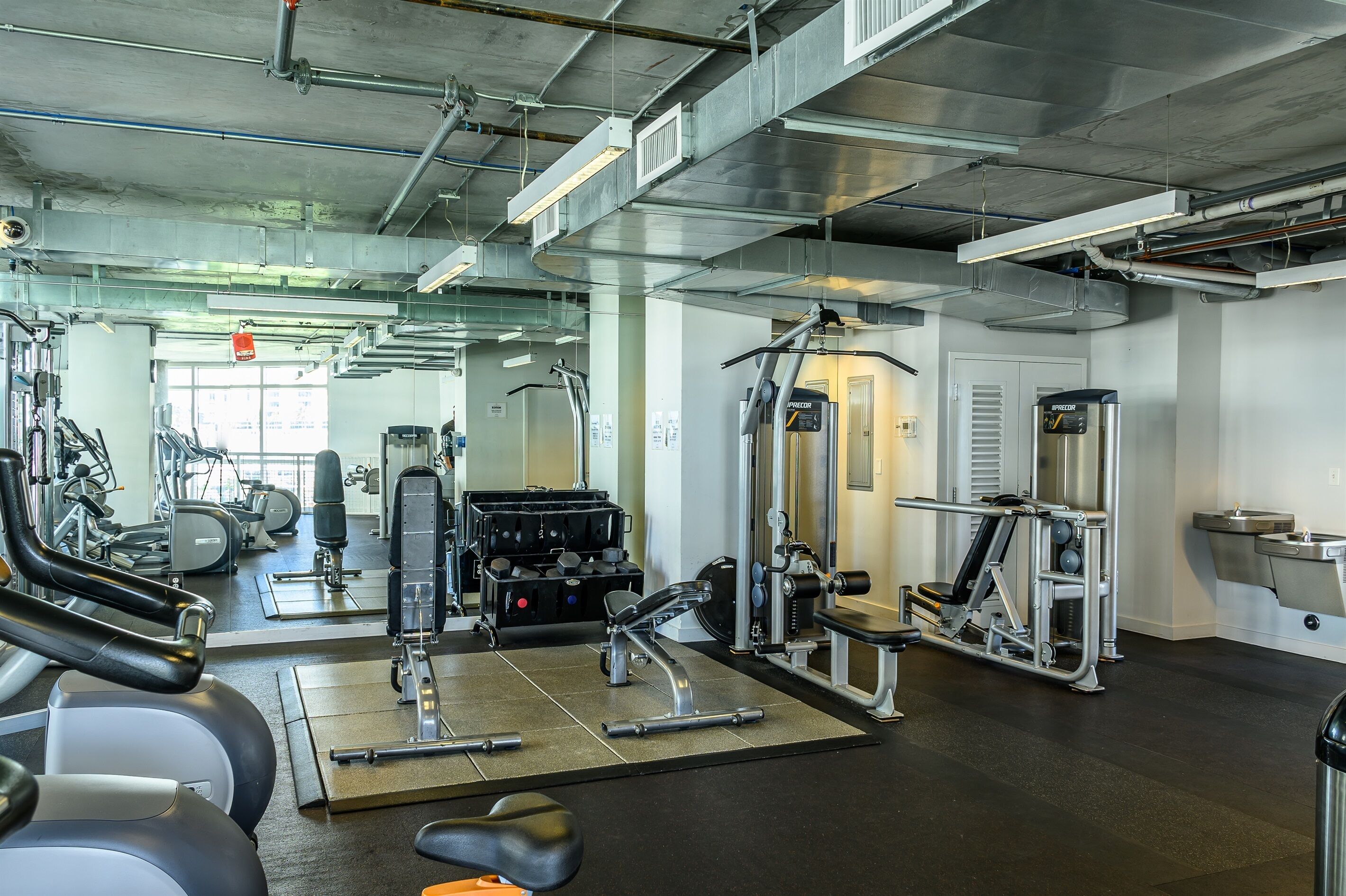 A gym with various exercise equipment, including treadmills, weight machines, and free weights.