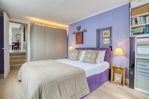 A bedroom with a bed, bedside tables, a bookshelf, and a door leading to a staircase. - Beautifully Presented 1BD Flat in West London (London)