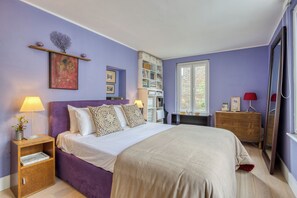 A bedroom with a bed, bedside tables, a dresser, a bookshelf, and a window.