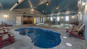 An indoor swimming pool area with lounge chairs, ceiling fans, and a small Christmas tree.