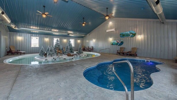 An indoor swimming pool with a diving board, ceiling fans, and Christmas trees.